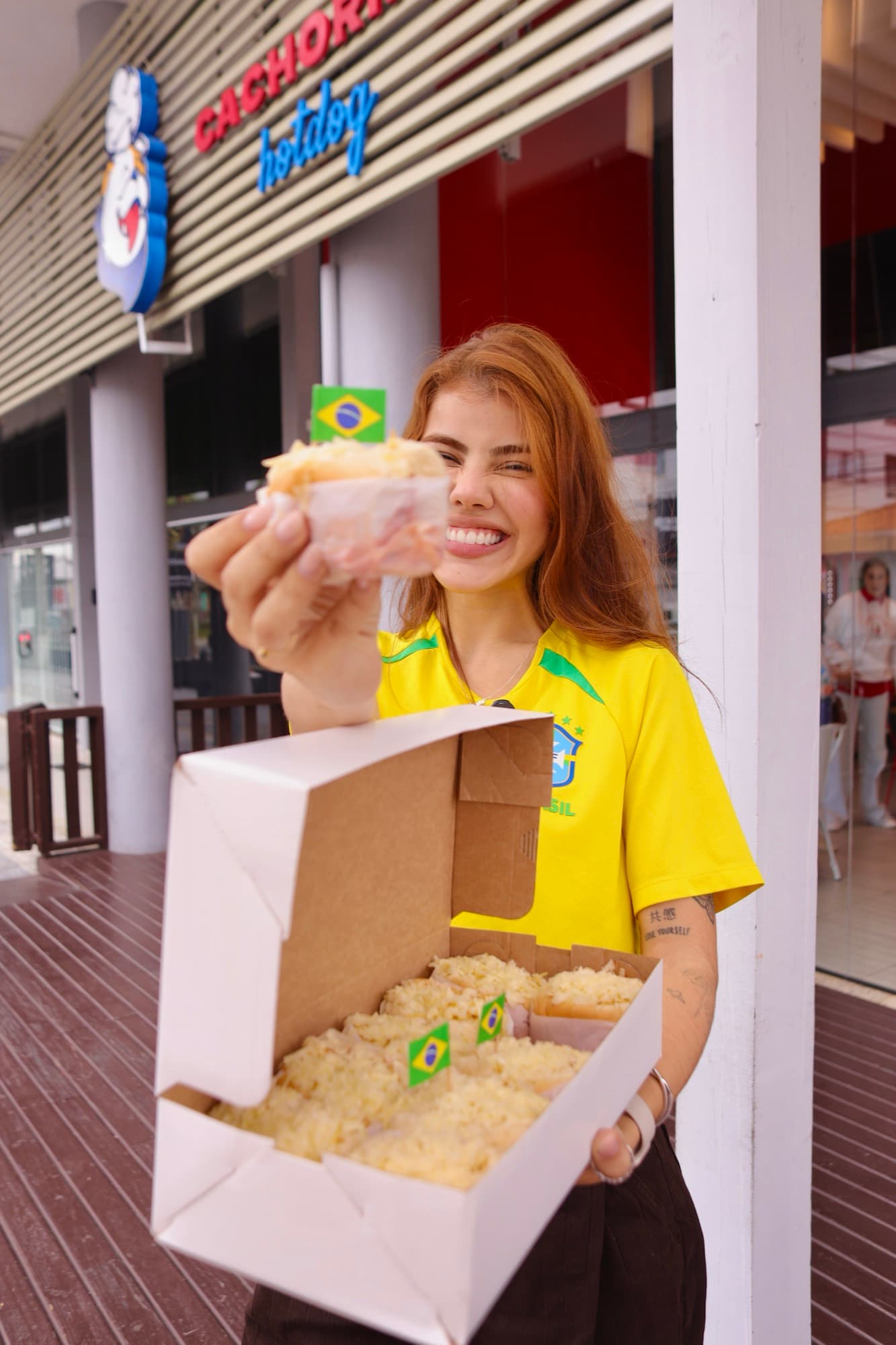 Cliente com a camisa do Brasil segurando um mini-dog do Cachorrão